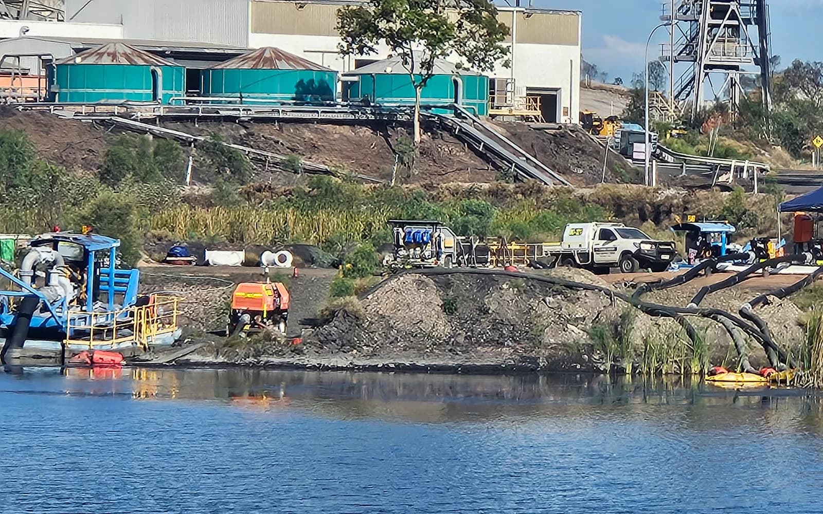 Pump station and pipework on the water of the Stockpile Dam at Clermont Coal Mine, with the plant behind