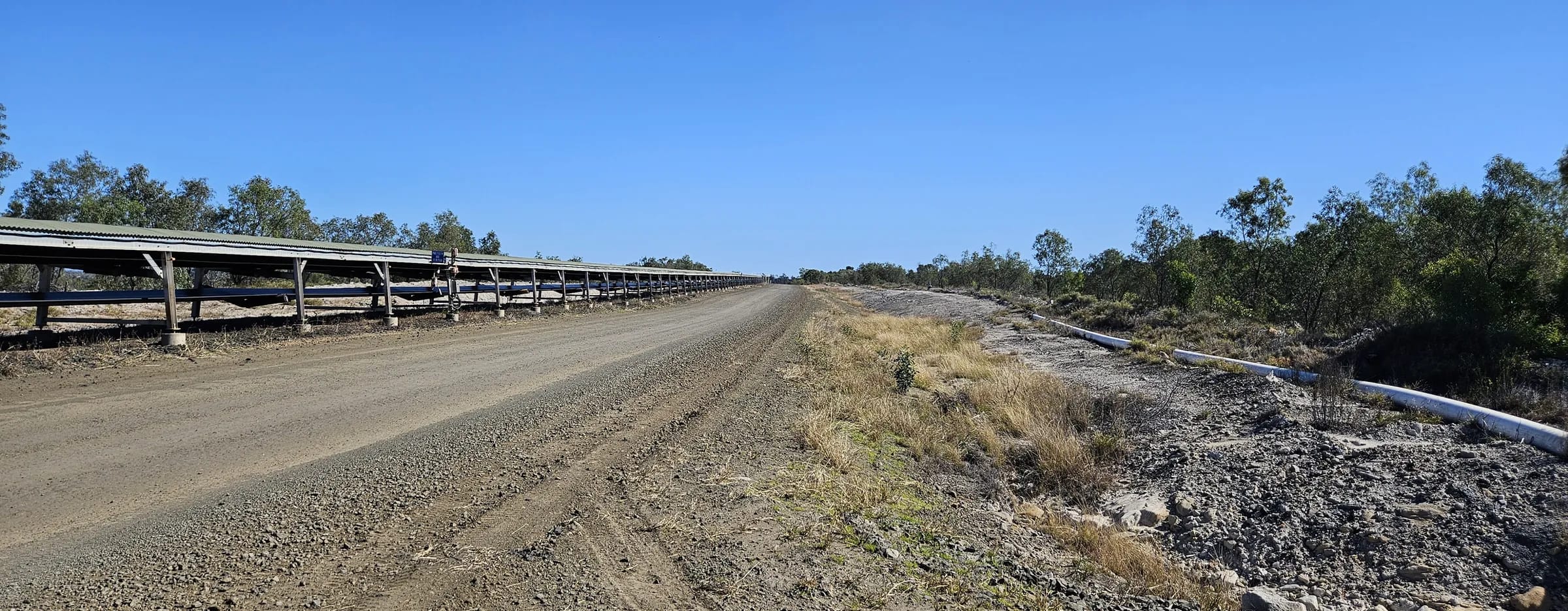 Overland conveyor and service road beside mine rehabilitation