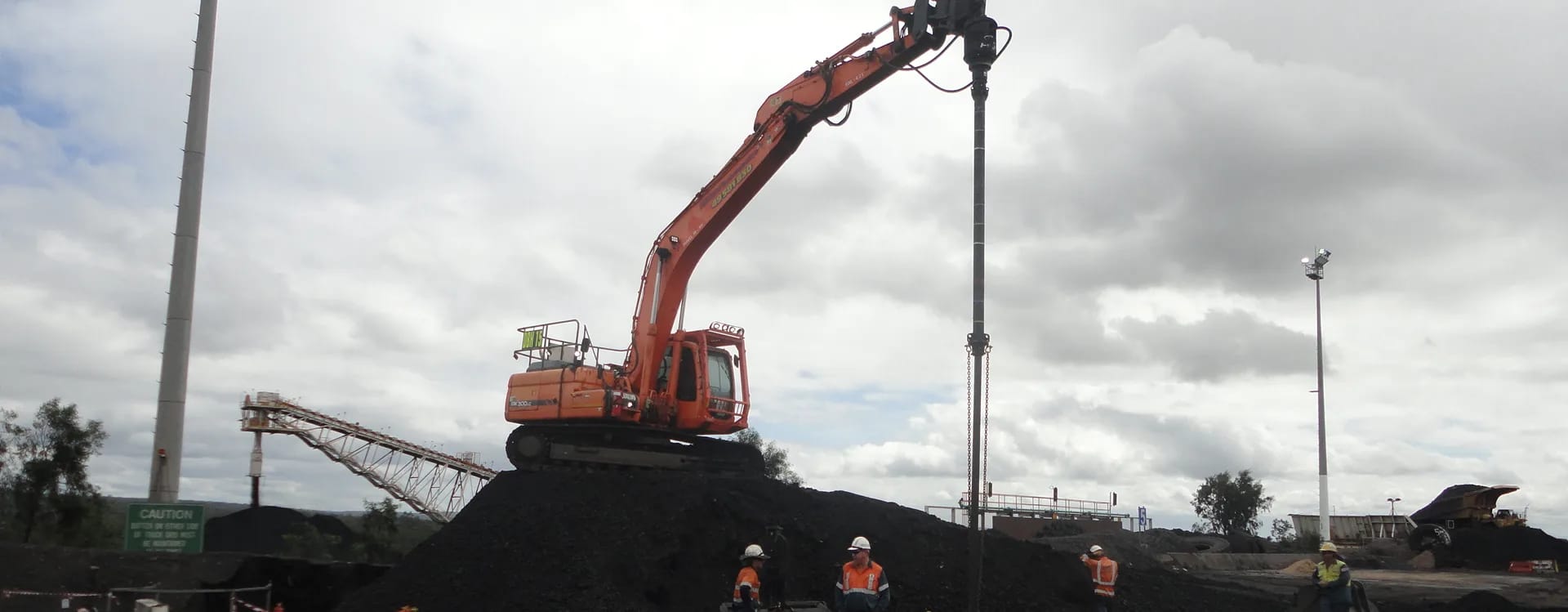 Piling rig on a coal stockpile at Saraji Mine, with a conveyor and a lighting tower behind